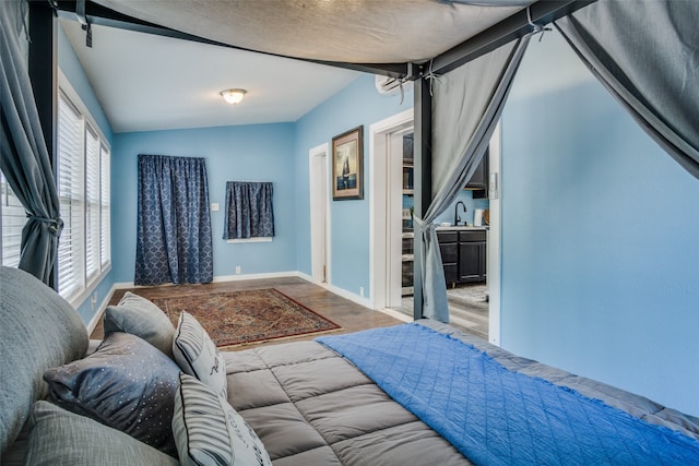 bedroom featuring wood-type flooring, sink, and lofted ceiling