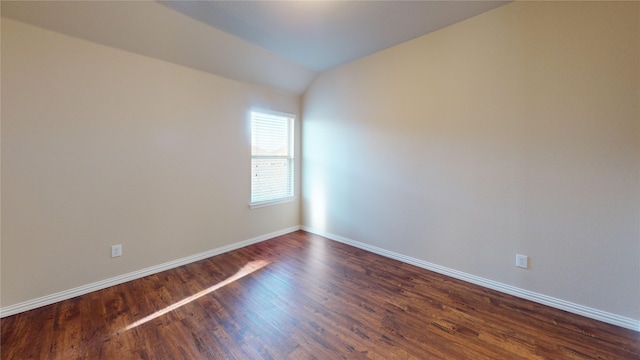 unfurnished room featuring lofted ceiling and dark hardwood / wood-style flooring