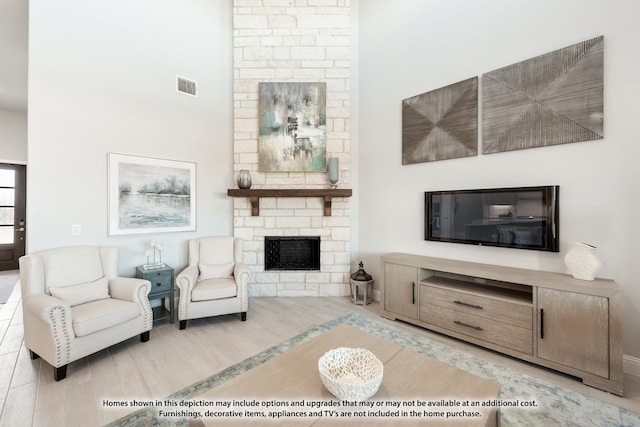 living room featuring a stone fireplace, hardwood / wood-style flooring, and brick wall