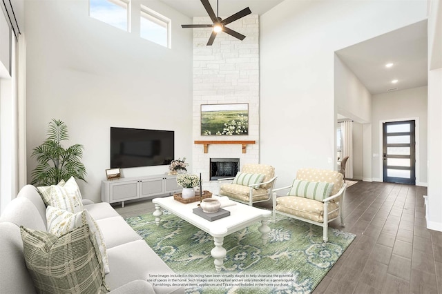 living room with a towering ceiling, a wealth of natural light, a large fireplace, and dark wood-type flooring