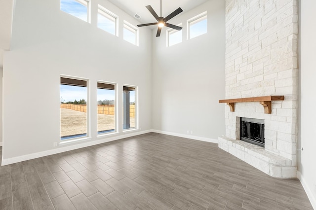 living room with a fireplace, light hardwood / wood-style flooring, and a towering ceiling