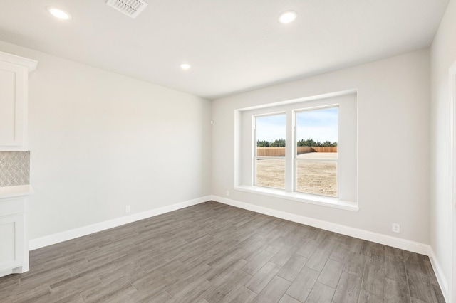 empty room with recessed lighting, wood finished floors, visible vents, and baseboards