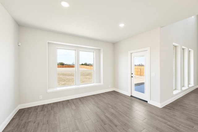 empty room featuring recessed lighting, baseboards, and wood finished floors