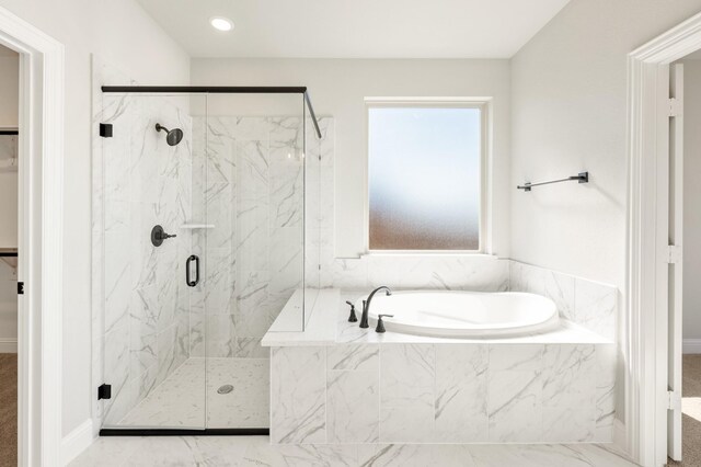 bathroom featuring a garden tub, a marble finish shower, and a walk in closet