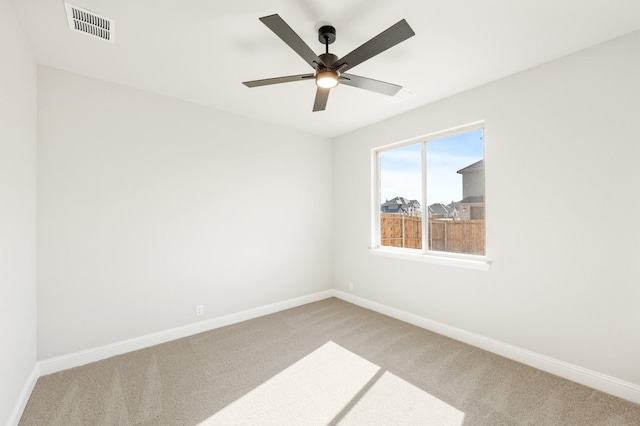 empty room featuring a ceiling fan, carpet, visible vents, and baseboards