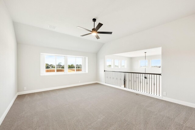 carpeted spare room with lofted ceiling, visible vents, baseboards, and a ceiling fan