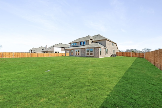 back of property featuring central AC, brick siding, a lawn, and a fenced backyard