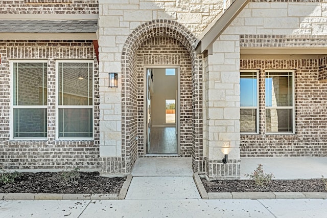 entrance to property featuring stone siding and brick siding