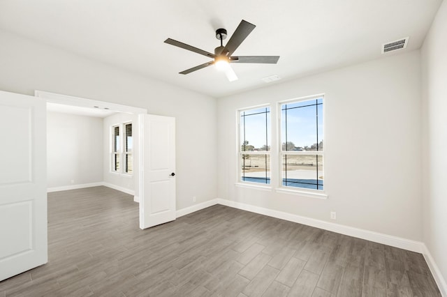 empty room with visible vents, baseboards, and wood finished floors