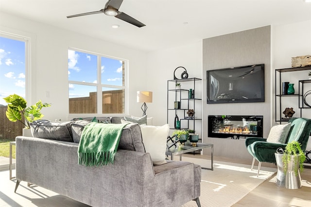 living room with a fireplace, light wood-type flooring, and ceiling fan