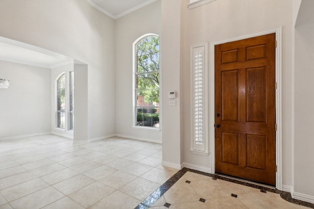 tiled foyer entrance featuring crown molding, plenty of natural light, and a towering ceiling