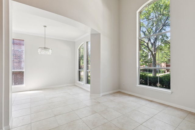 tiled empty room featuring crown molding, plenty of natural light, and an inviting chandelier