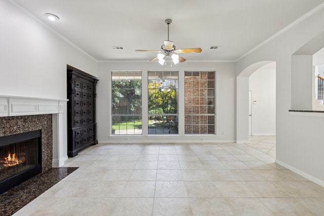 unfurnished living room featuring ceiling fan, crown molding, a premium fireplace, and light tile patterned floors