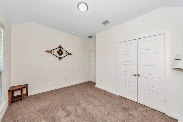 unfurnished bedroom with carpet floors, a closet, visible vents, vaulted ceiling, and baseboards