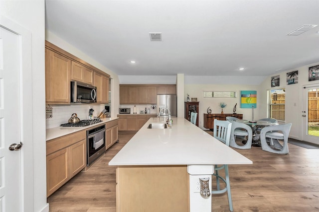 kitchen with light wood-type flooring, visible vents, stainless steel appliances, and a sink