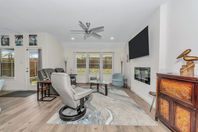 living area with recessed lighting, baseboards, a fireplace, and light wood finished floors