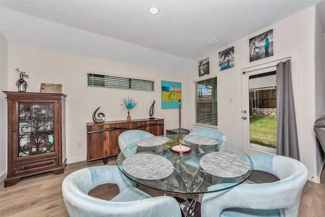 dining area with vaulted ceiling, baseboards, and wood finished floors