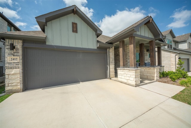 view of front of house featuring brick siding, board and batten siding, a garage, stone siding, and driveway