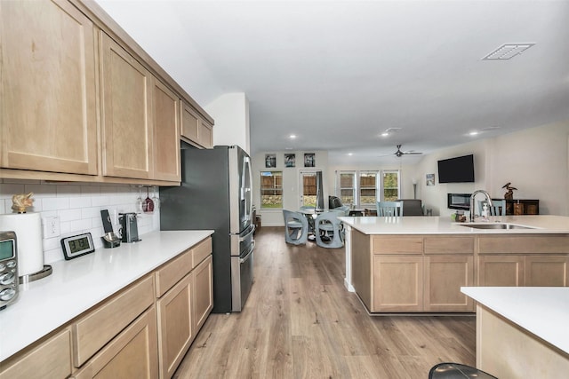 kitchen featuring a sink, light countertops, backsplash, light brown cabinetry, and light wood finished floors