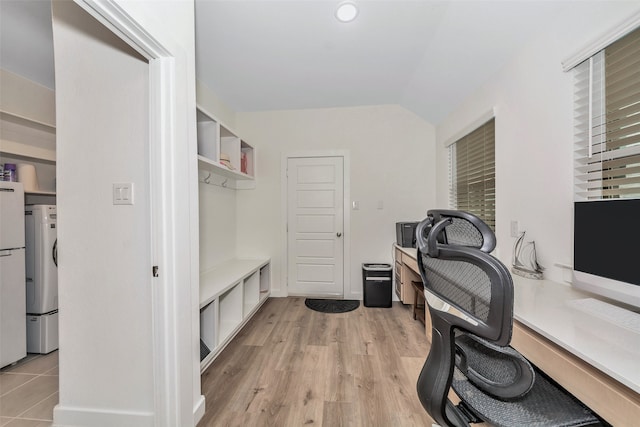 office area featuring stacked washer / dryer, lofted ceiling, and light hardwood / wood-style floors