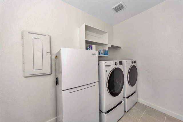 laundry room featuring washing machine and clothes dryer, light tile patterned floors, visible vents, laundry area, and baseboards