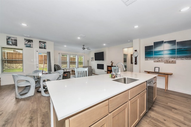 kitchen with a center island with sink, sink, wood-type flooring, and light brown cabinetry