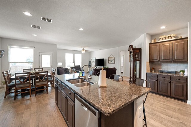 kitchen with a center island with sink, a textured ceiling, dishwasher, light hardwood / wood-style flooring, and sink