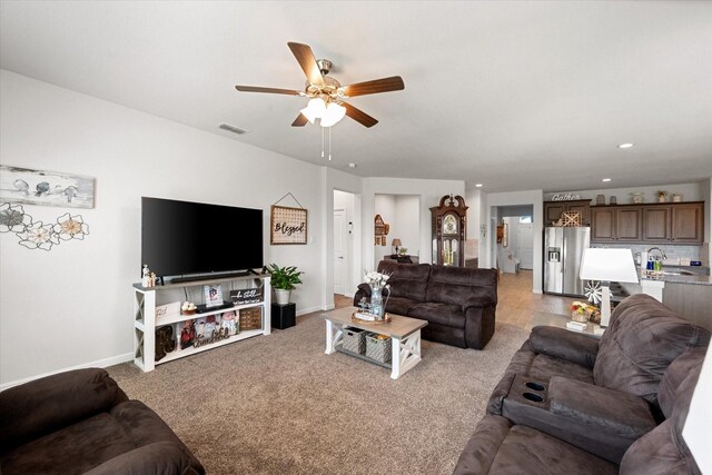 living room featuring light carpet, sink, and ceiling fan