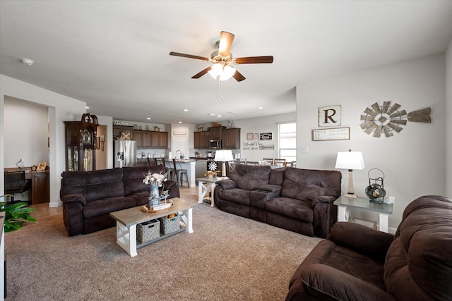 living room featuring light carpet, sink, and ceiling fan