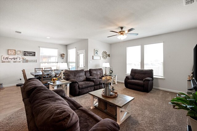 living room with a textured ceiling, light colored carpet, and ceiling fan