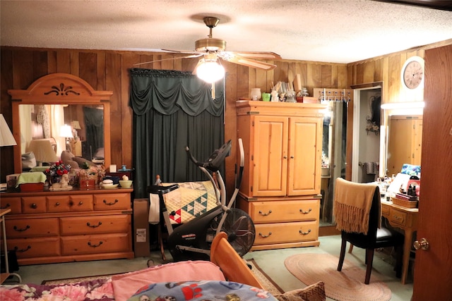 carpeted bedroom featuring ceiling fan, a textured ceiling, and wooden walls