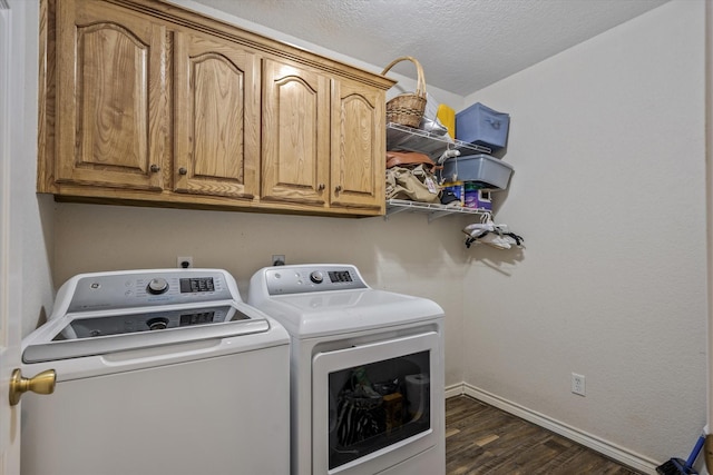 clothes washing area with cabinet space, dark wood-type flooring, washing machine and dryer, a textured ceiling, and baseboards