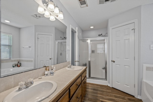 bathroom featuring dual vanity, wood-type flooring, and separate shower and tub