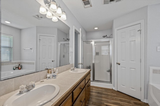 full bath with a garden tub, visible vents, a sink, and wood finished floors