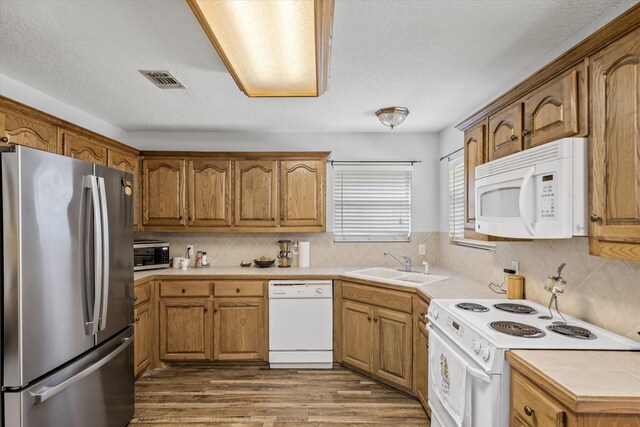 kitchen featuring a textured ceiling, white appliances, decorative backsplash, hardwood / wood-style floors, and sink