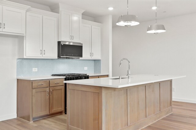 kitchen featuring a kitchen island with sink, light hardwood / wood-style flooring, white cabinets, and pendant lighting