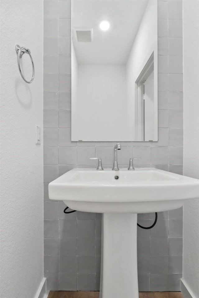 bathroom featuring backsplash, tile walls, and sink