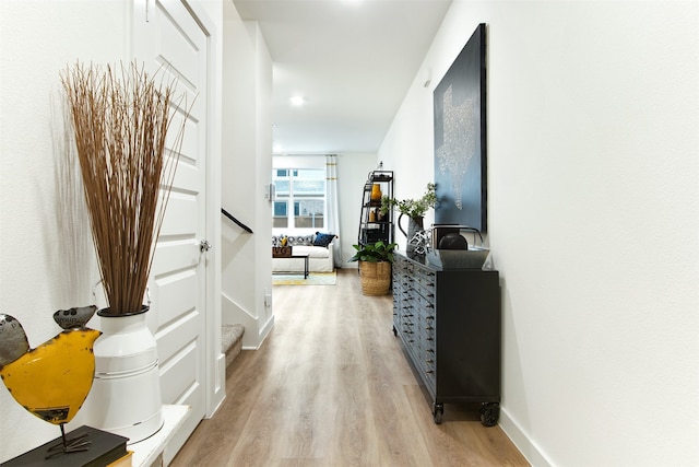 hall featuring stairs, light wood-style floors, and baseboards