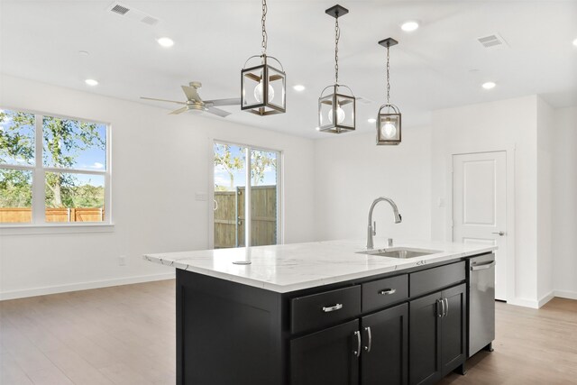 kitchen with sink, light stone counters, decorative light fixtures, dishwasher, and an island with sink