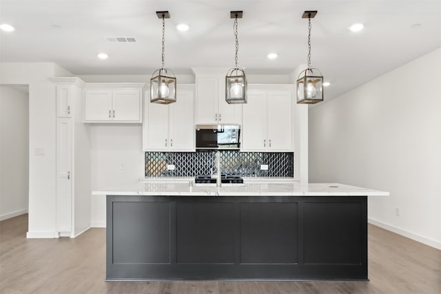 kitchen featuring an island with sink, light hardwood / wood-style flooring, white cabinets, and decorative light fixtures