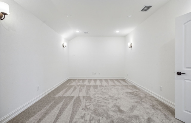 carpeted empty room with vaulted ceiling