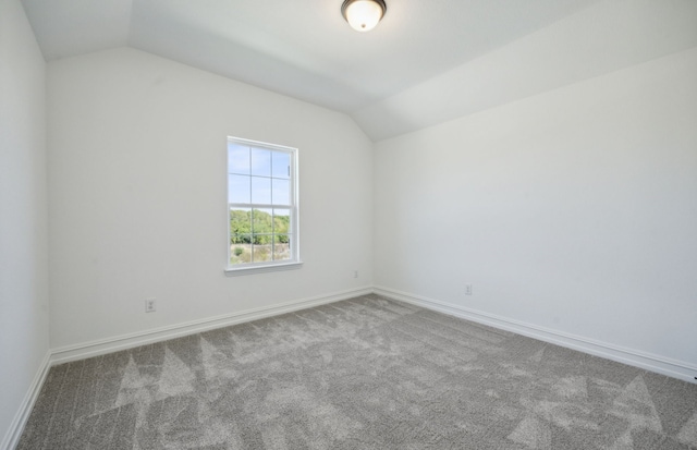 spare room featuring carpet and lofted ceiling