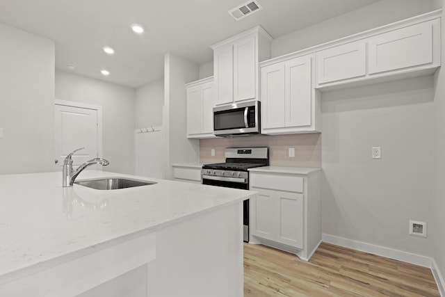 kitchen with white cabinetry, appliances with stainless steel finishes, sink, and backsplash