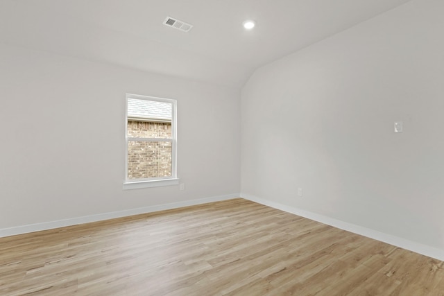 spare room with vaulted ceiling and light wood-type flooring