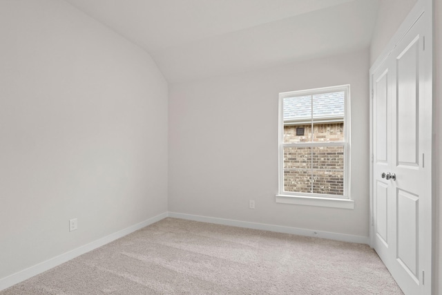 unfurnished room featuring light colored carpet and vaulted ceiling