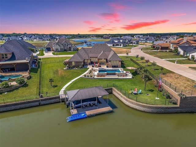 aerial view at dusk with a residential view and a water view