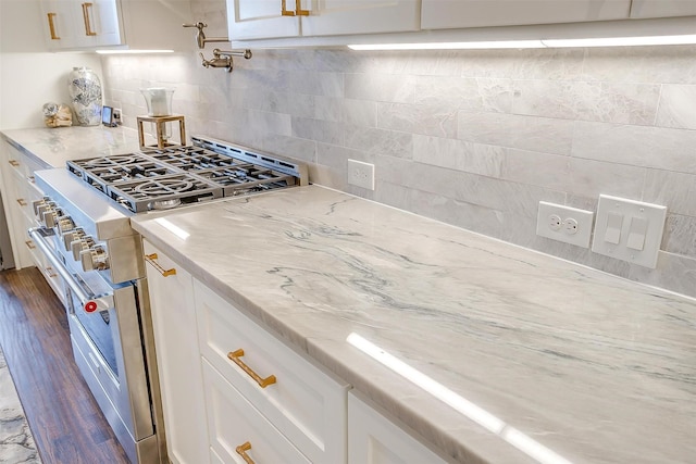 kitchen featuring high end stove, light stone countertops, and white cabinets