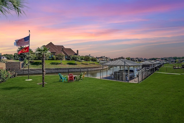 yard at dusk featuring a gazebo, a water view, and fence