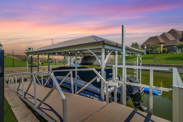 dock area with a water view, boat lift, and fence