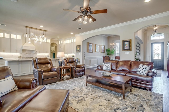 living room with recessed lighting, arched walkways, wood finished floors, and ornamental molding